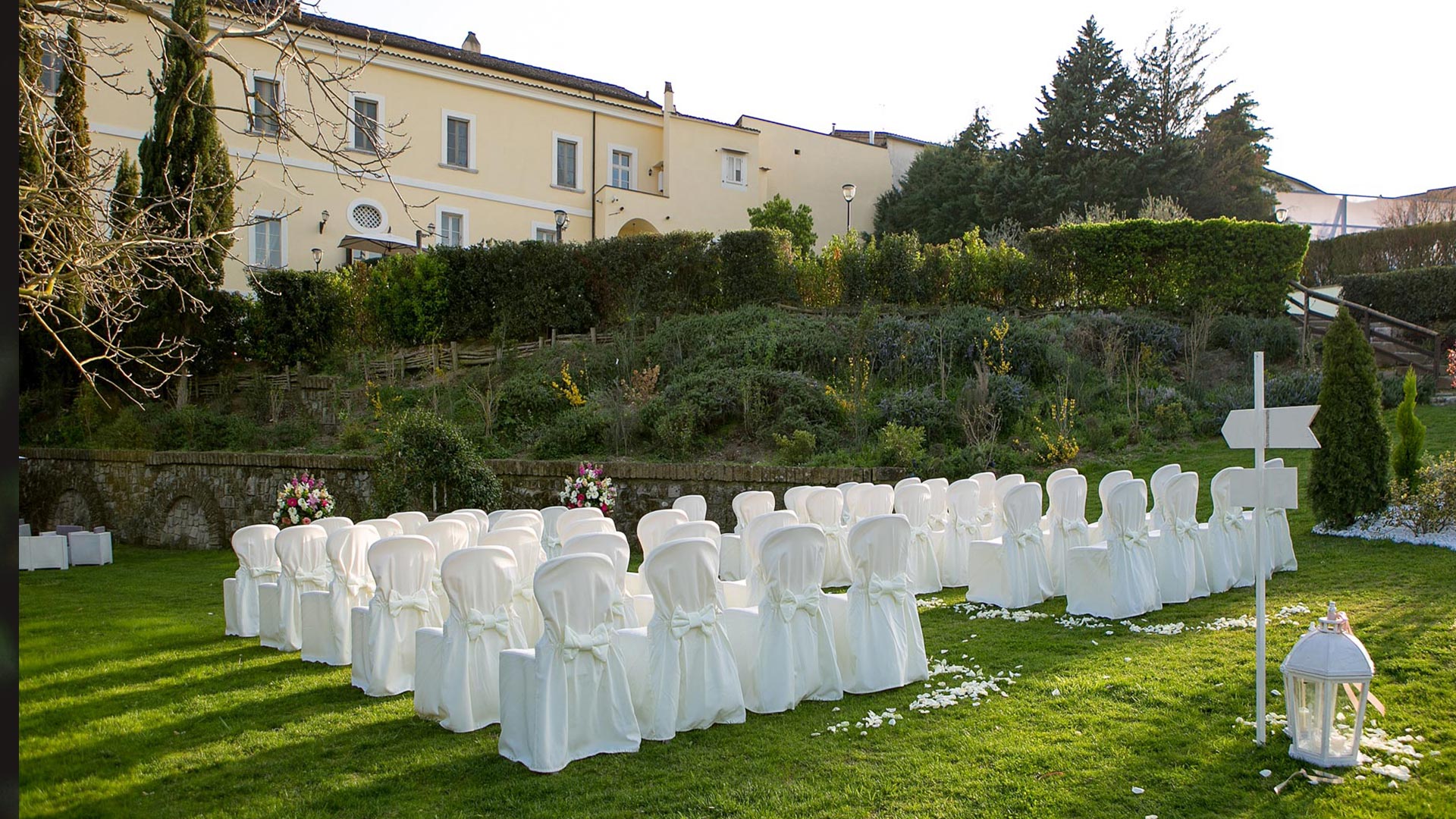 sedie bianche in giardino per la celebrazione in un ristorante moderno per matrimoni a Caserta
